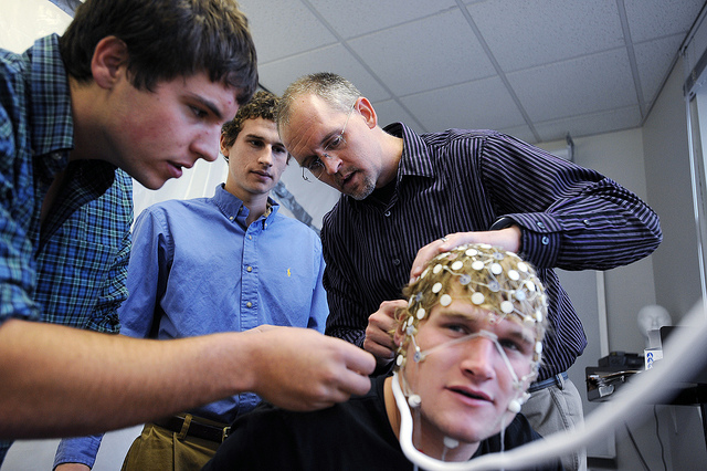 Eric Hall, professor of exercise science, works with Elon University students Mark Sundman, Drew Gardner and Chris Fry (test subject) to measure cognitive functions in research used to study the effects of concussions.