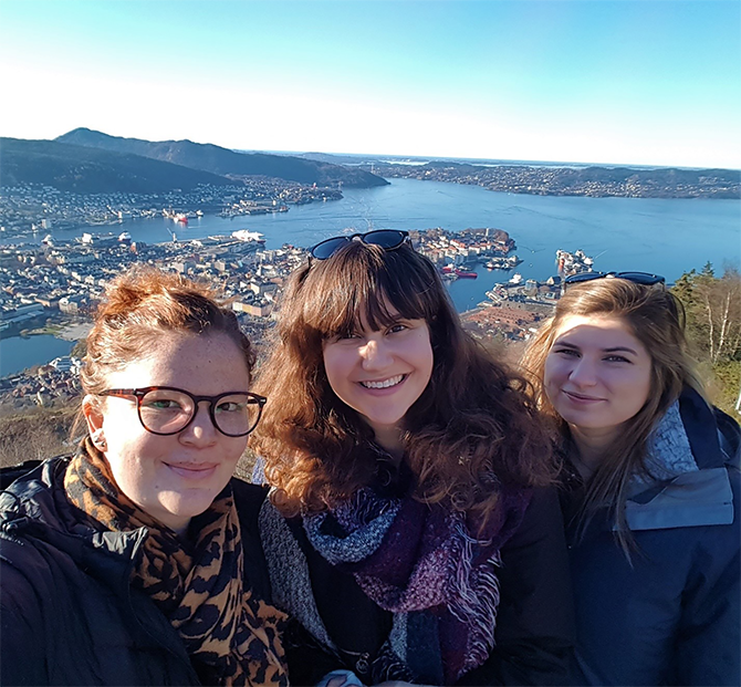 Lucy Mercer-Mapstone, Rachel Guitman, and Anita Acai smiling, with mountains and lake in background