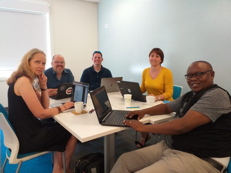 This picture shows international the authors sitting around a table, collaboratively working together