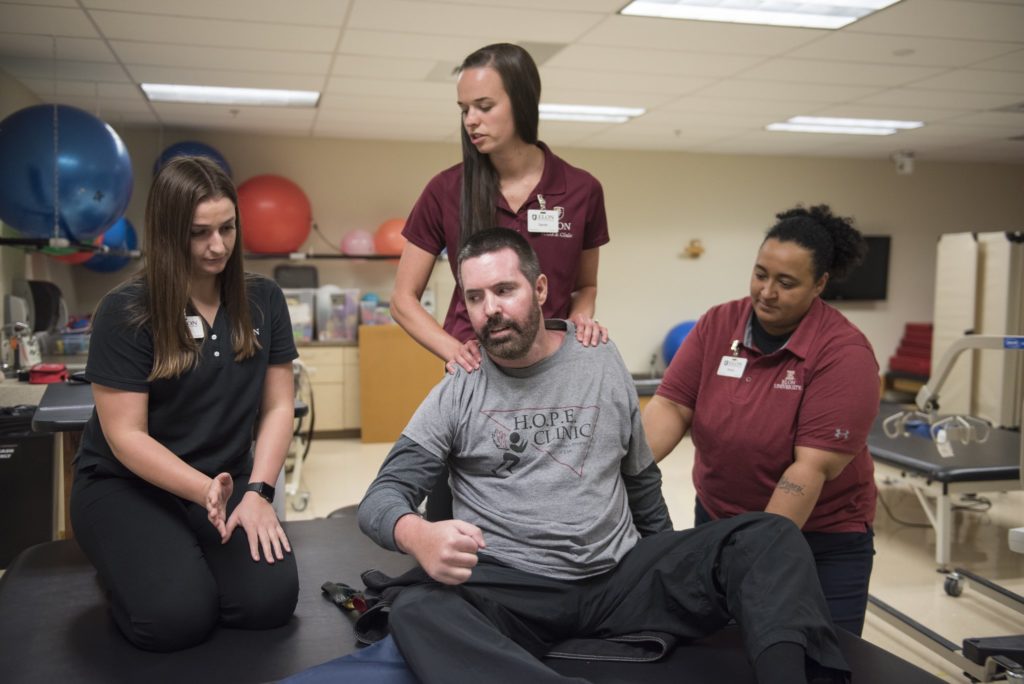 Students and instructors in physical therapy treat a patient.