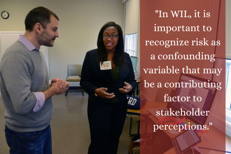 A student and a faculty stand in a classroom talking near an open laptop. "In WIL, it is important to recognize risk as a confounding variable that may be a contributing factor to stakeholder perceptions."