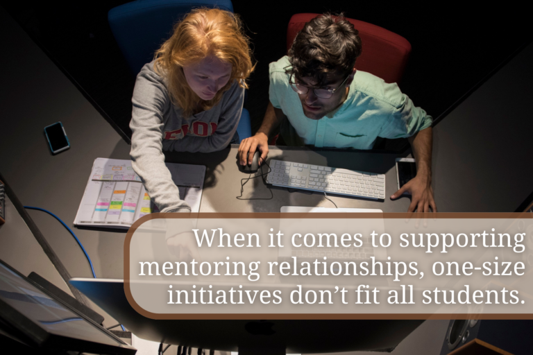 two students sit in front of a computer screen. One of them points at the computer while the other looks at it. "When it comes to supporting mentoring relationships, one-size initiatives don't fit all relationships"
