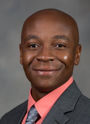 headshot of a man wearing a suit and tie