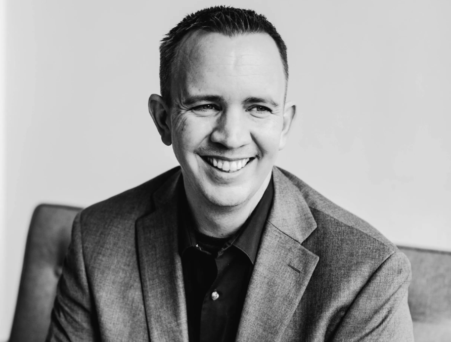 Headshot of a man wearing a blazer. He's smiling and looking slightly right of camera.