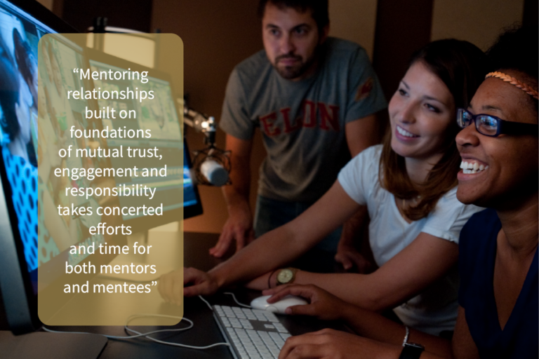 A faculty member and two students gathered by a computer with an extended monitor, looking together at a video editing project. A text overlay reads, "Mentoring relationships built on foundations of mutual trust, engagement, and responsibility take concerted efforts and time for both mentors and mentees."
