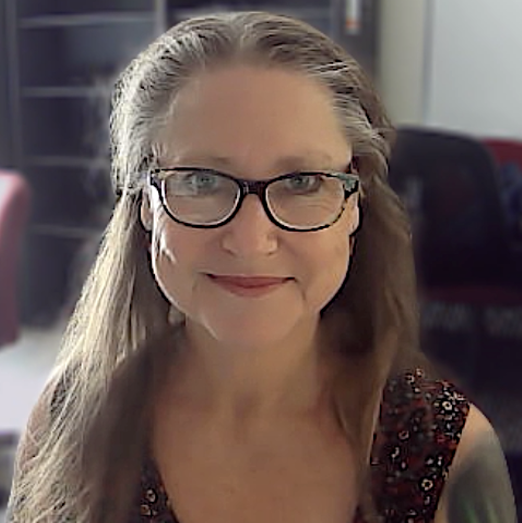 White woman with glasses and hair pulled back.