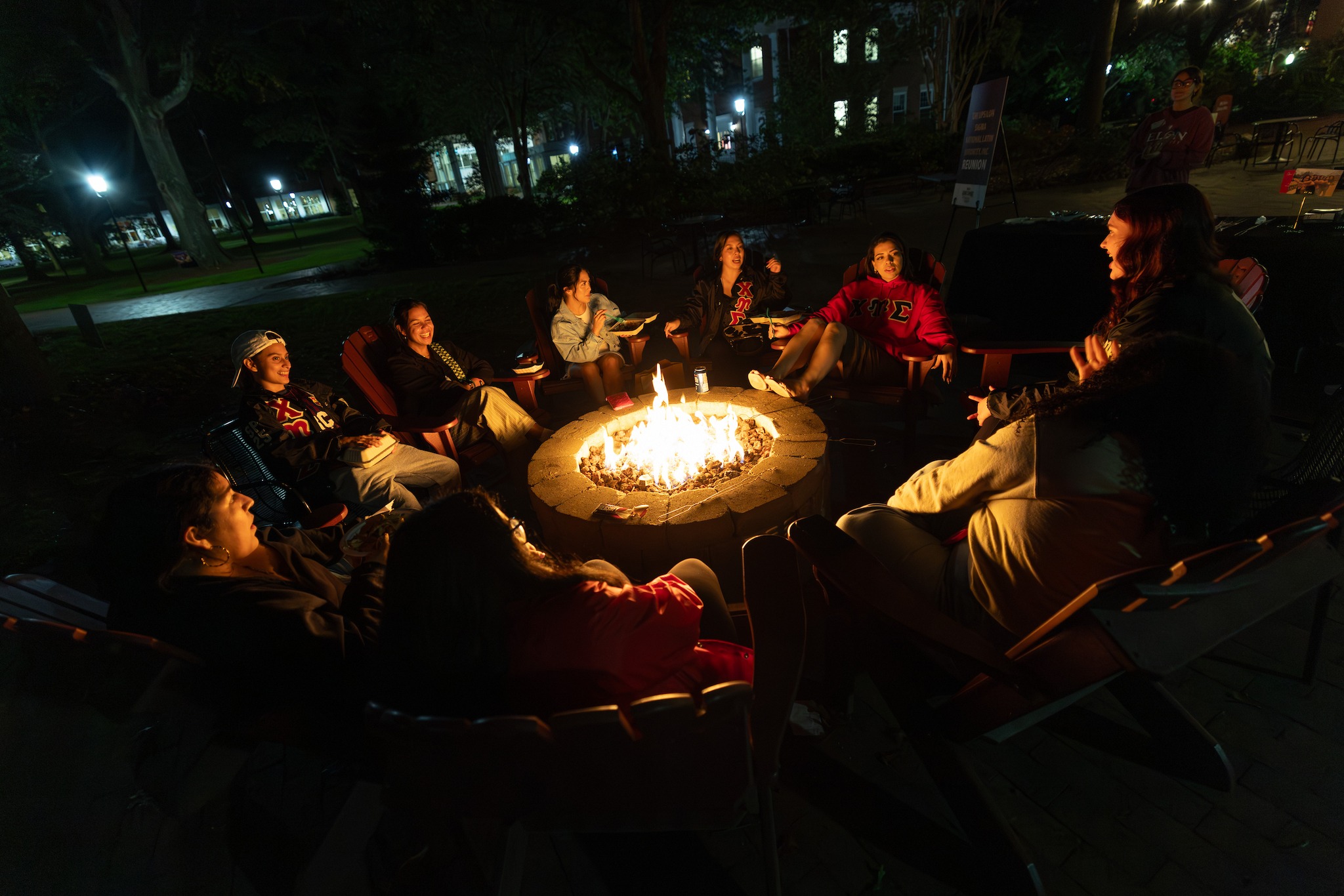 Students gather around a fire pit at night at Elon University