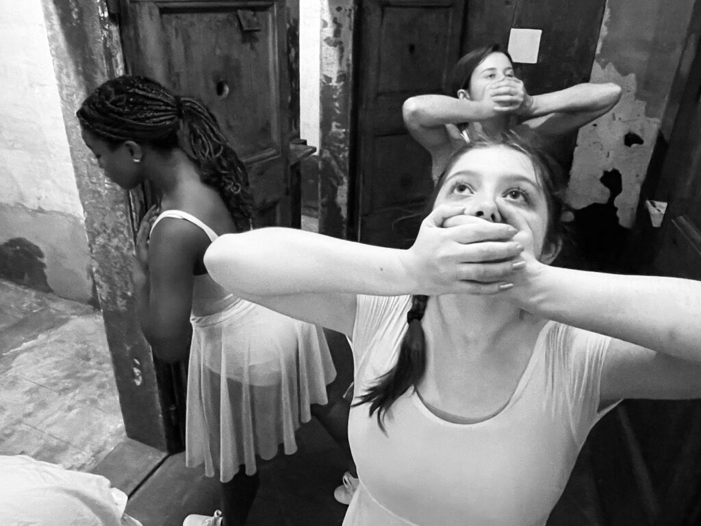 Three student dancers in rustic location interacting with walls, each facing different directions