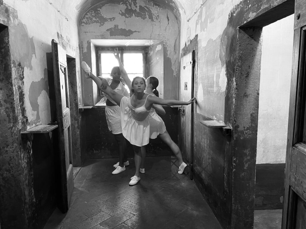 Three student dancers in rustic location interacting with each other in a hallway