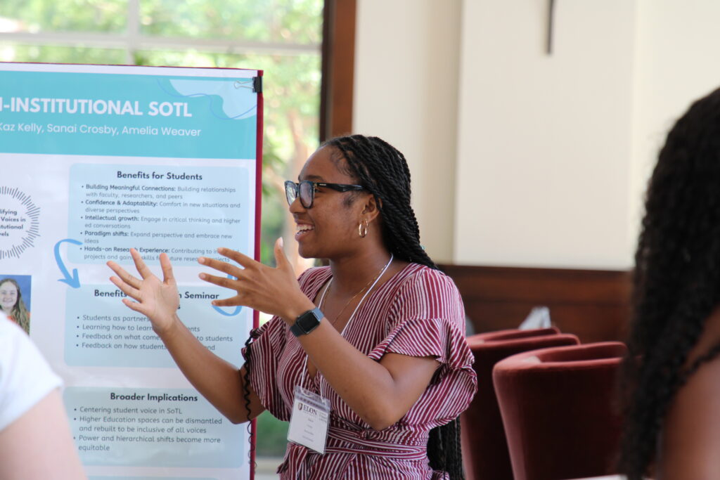 Student presenter speaking animatedly in from of research poster. 